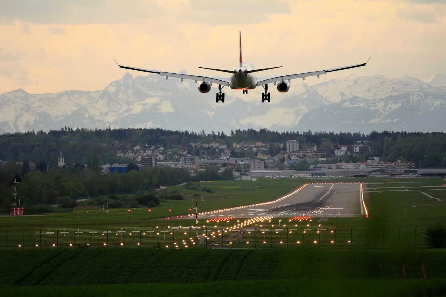An aircraft landing with snow-capped mountains behind
