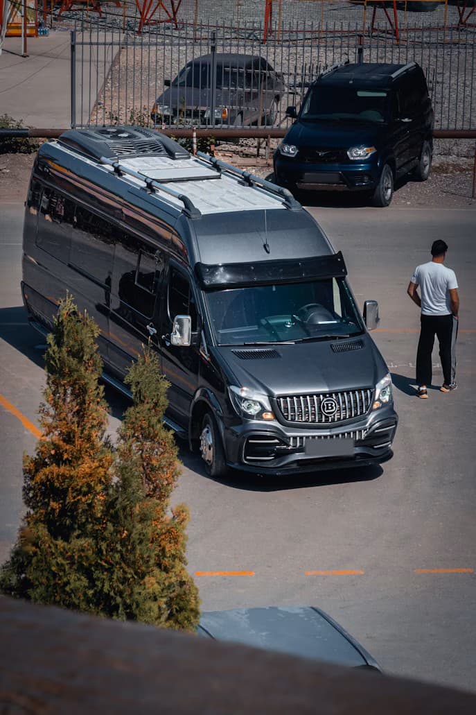 A dark grey executive minibus parked in a car park